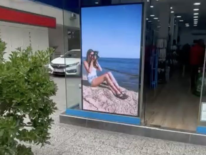 Mağaza vitrininde cam arkasına yerleştirilmiş dikey LED ekran, gün ışığında